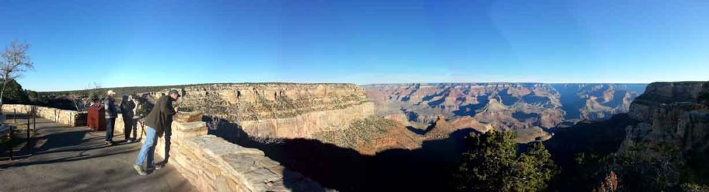 People stand behind a wall to safely view the Grand Canyon